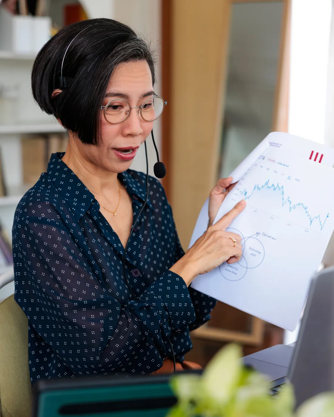 Illustrative photograph: a person wearing a headset and holding a printed report with a chart.